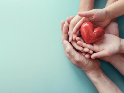 Adult's and child's hands holding a red heart