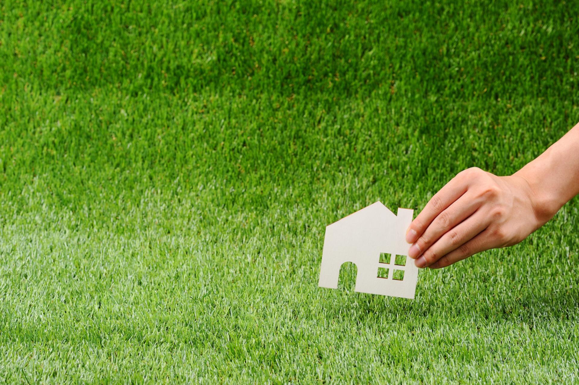 Hand holding white house shaped cut out