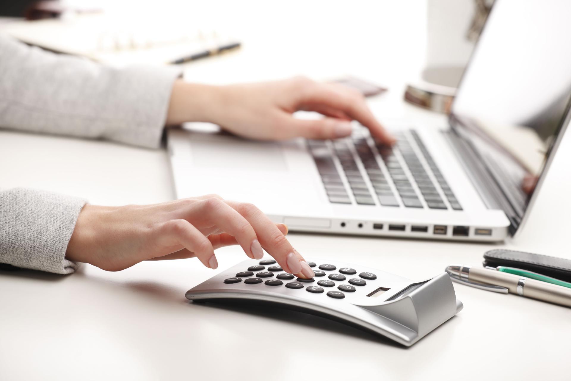 Woman using calculator and laptop computer