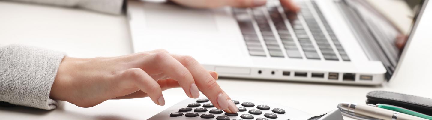 Woman using calculator and laptop computer