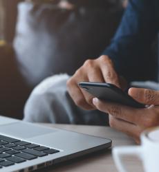 Man using mobile phone whilst sat at a computer